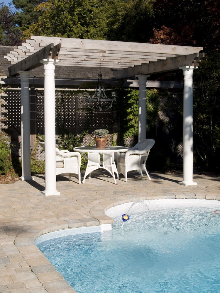 A poolside pergola above a small wicker dining set. The pergola doesn't provide a lot of shade, but is the perfect small, unobtrusive structure to hang a wrought iron chandelier. A poolside pergola above a small wicker dining set. The pergola doesn't provide a lot of shade, but is the perfect small, unobtrusive structure to hang a wrought iron chandelier.