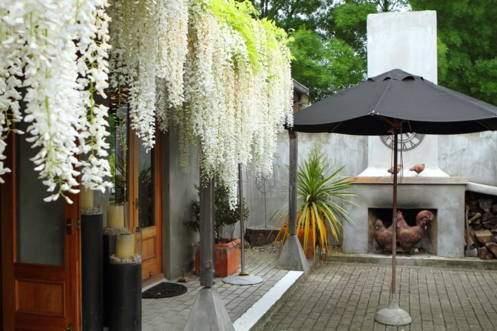 This fireplace is built into a concrete wall and takes on a much more rustic look when paired with the hanging, trailing flowers flowing like a waterfall over the roof. This fireplace is built into a concrete wall and takes on a much more rustic look when paired with the hanging, trailing flowers flowing like a waterfall over the roof.