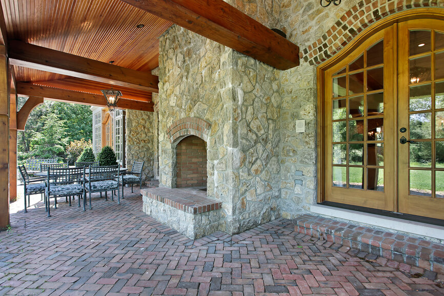 This fireplace is built against the side of the home's stone facade, blending perfectly. It extends through the top of the wooden roof of the patio and has a raised hearth that matches the brick of the patio. This fireplace is built against the side of the home's stone facade, blending perfectly. It extends through the top of the wooden roof of the patio and has a raised hearth that matches the brick of the patio.