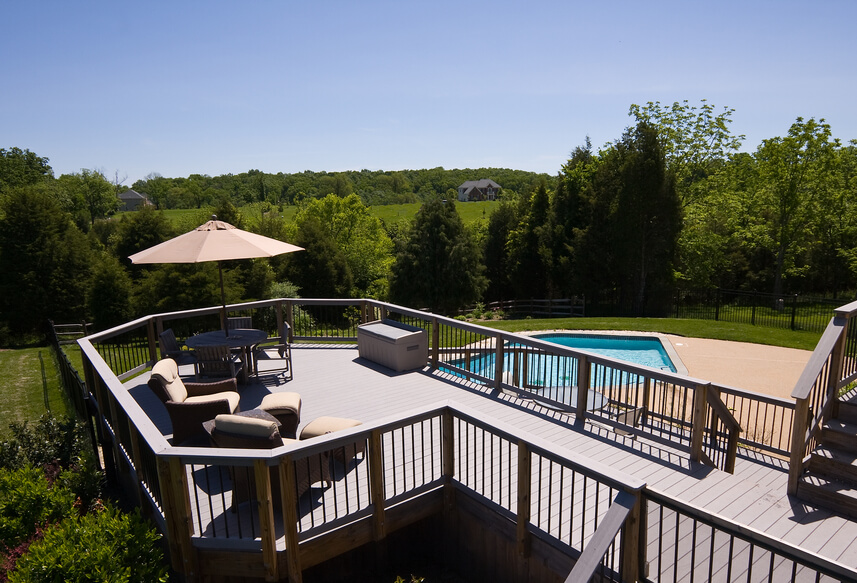 A raised deck overlooking a swimming pool. This deck is surrounded on all sides by a railing and has several different tiers. A raised deck overlooking a swimming pool. This deck is surrounded on all sides by a railing and has several different tiers.