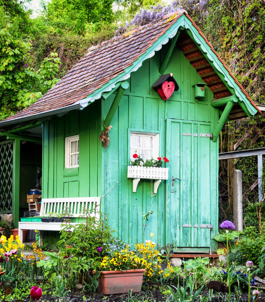 Painted a bright green, this ramshackle garden shed stands out against the surrounding planting beds. A small picket window box and a matching bench stand out against the bright green. Painted a bright green, this ramshackle garden shed stands out against the surrounding planting beds. A small picket window box and a matching bench stand out against the bright green.