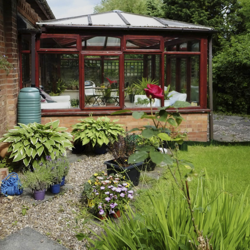 This greenhouse has been combined with a sunroom for a conservatory feel. The building is attached to the rear of the house and is accessible from either the yard or from inside the home. This greenhouse has been combined with a sunroom for a conservatory feel. The building is attached to the rear of the house and is accessible from either the yard or from inside the home.