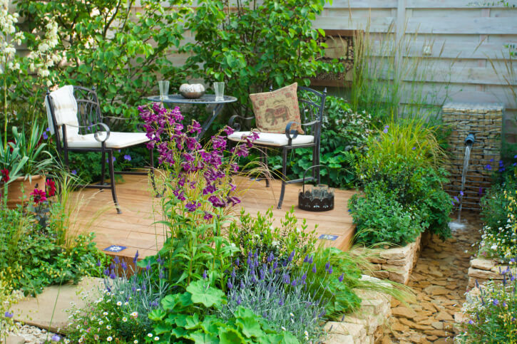 This lovely, small patio is tucked behind leafy plants and tall flowers in great variety. To the right is a man-made creek with a small fountain. This spot is perfectly relaxing with the addition of white noise. This lovely, small patio is tucked behind leafy plants and tall flowers in great variety. To the right is a man-made creek with a small fountain. This spot is perfectly relaxing with the addition of white noise.
