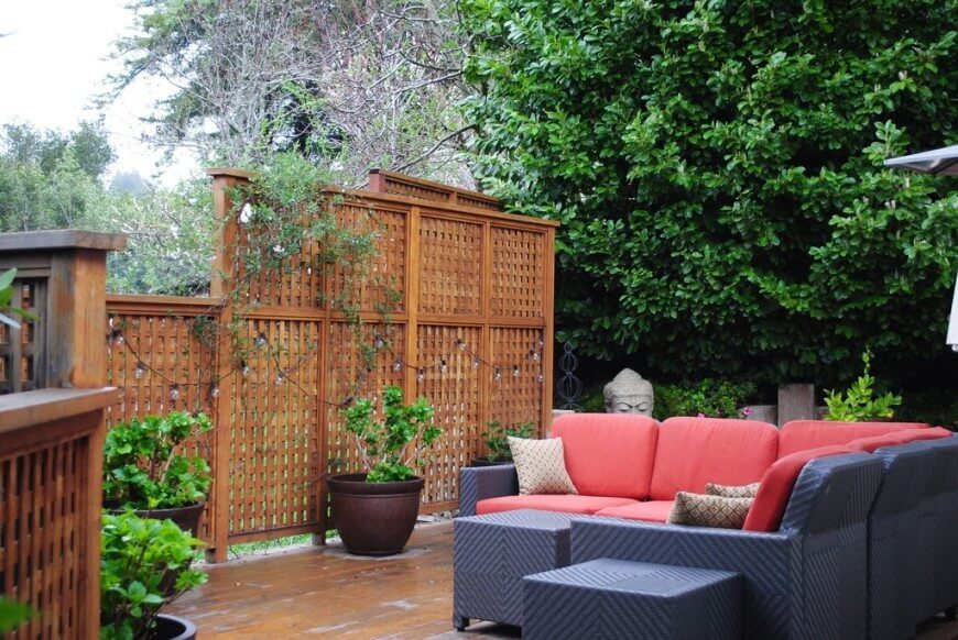 This latticed screen is decorated with a strand of lights and punctuated with contemporary containers of ornamental trees. This latticed screen is decorated with a strand of lights and punctuated with contemporary containers of ornamental trees.