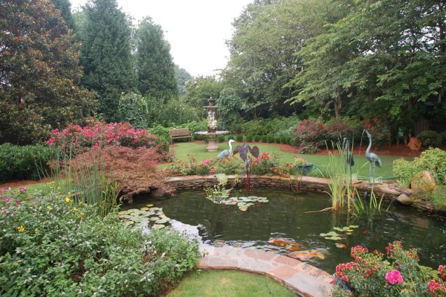 This enormous garden really takes advantage of the space available, adding a pool, egret statues, and a large fountain in the back corner with a bench from which to enjoy it all. This enormous garden really takes advantage of the space available, adding a pool, egret statues, and a large fountain in the back corner with a bench from which to enjoy it all.
