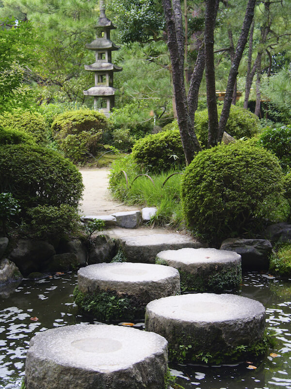 Large, flat stones are placed into the water to form a path across to the next section of this lovely Japanese garden. Large, flat stones are placed into the water to form a path across to the next section of this lovely Japanese garden.