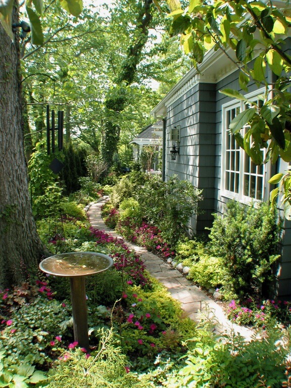 A simple pedestal bird bath with a removable top. The bird bath is tucked into a densely landscaped section off the flagstone path at the side of the home. A simple pedestal bird bath with a removable top. The bird bath is tucked into a densely landscaped section off the flagstone path at the side of the home.