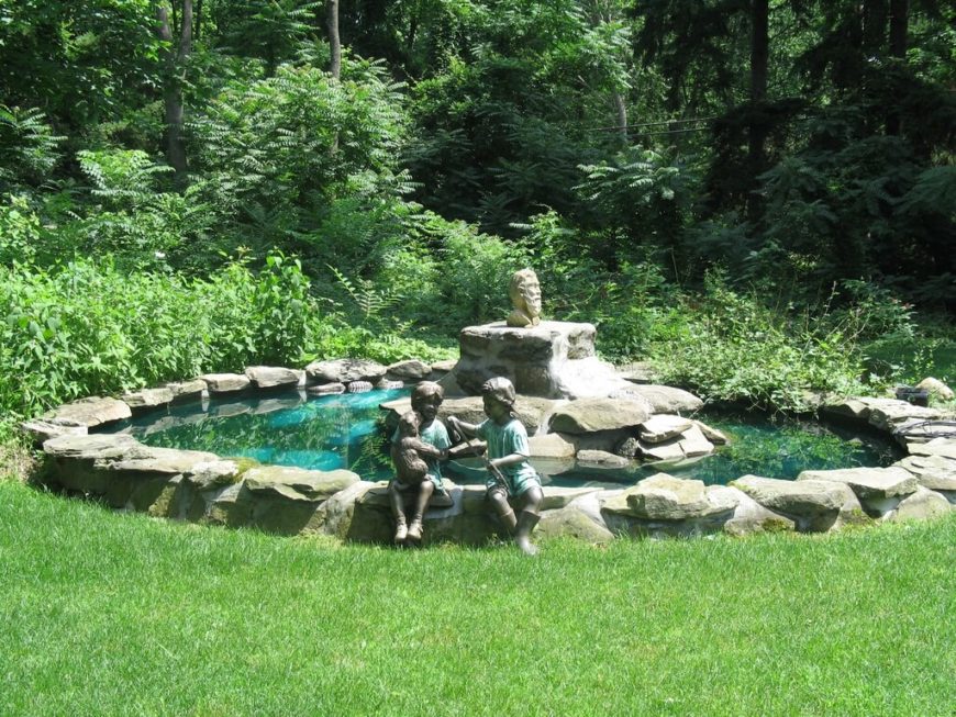 Statues can be placed on the edge of a pond, like these statues of children and a puppy placed as though sitting on the edge of this man made backyard pond. Statues can be placed on the edge of a pond, like these statues of children and a puppy placed as though sitting on the edge of this man made backyard pond.