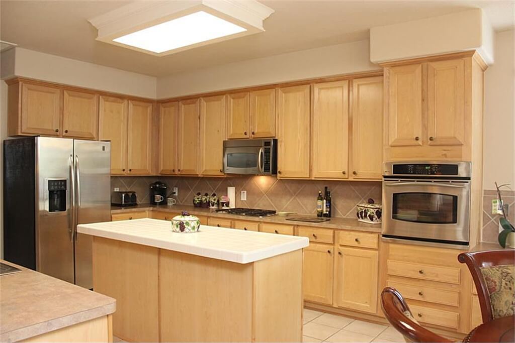 U-shaped kitchen with walnut cabinetry and counters along with a small center island equipped with smooth white countertop.