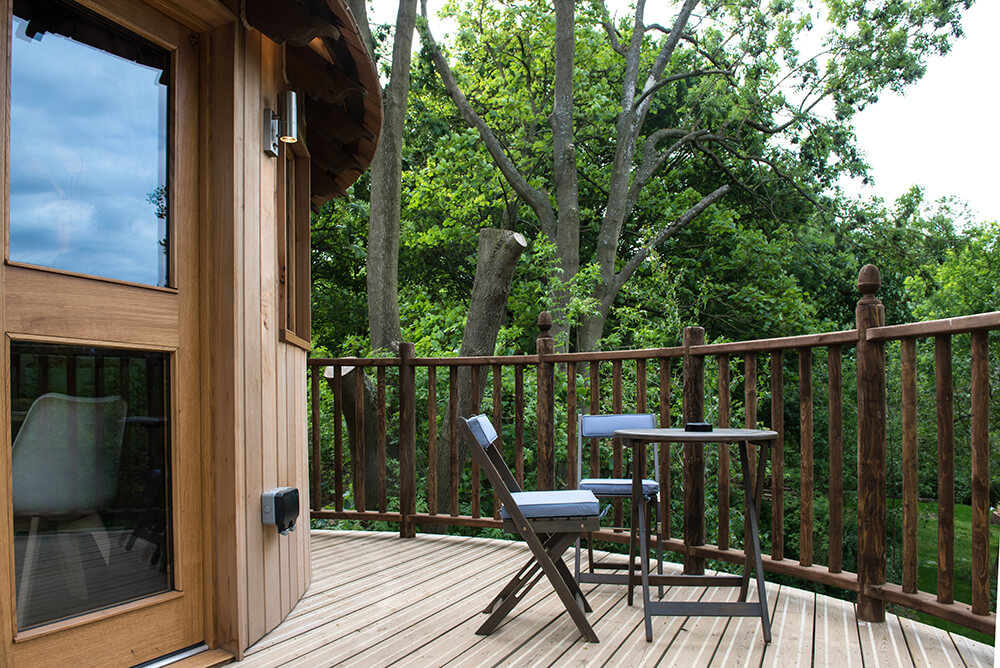 This deck features a small coffee table set overlooking the beautiful greenery outside.
