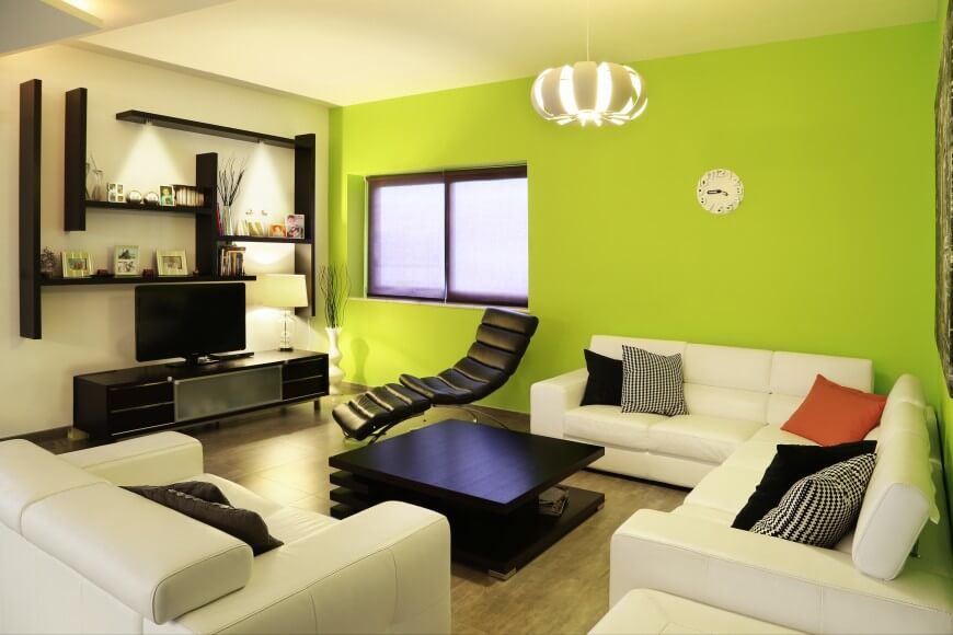 This modern living room uses a vibrant accent wall and a singular color pillow to add some vibrance to a monochromatic room. This modern living room uses a vibrant accent wall and a singular color pillow to add some vibrance to a monochromatic room.