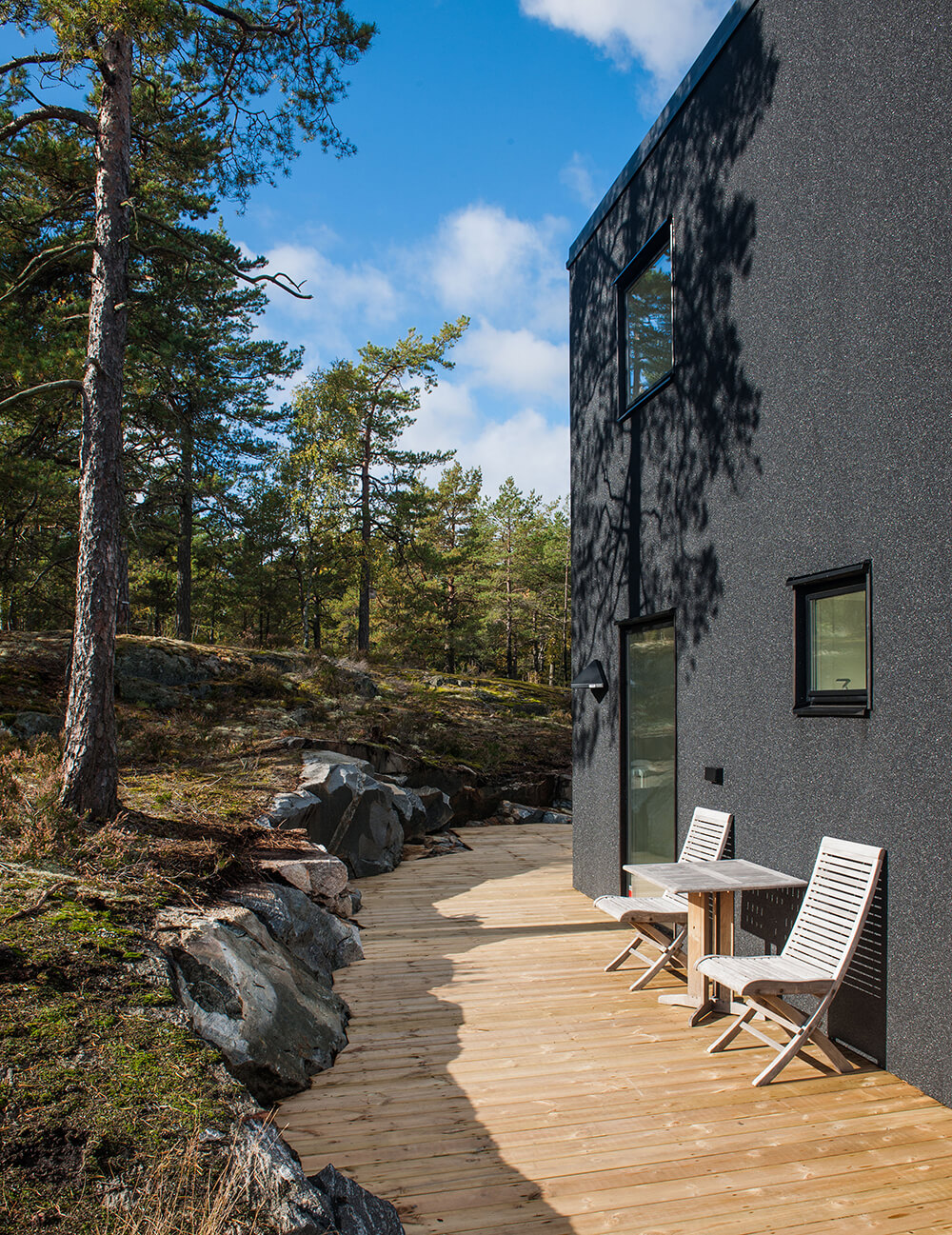 This deck features a lounger seats with a side table overlooking the beautiful outdoor area.