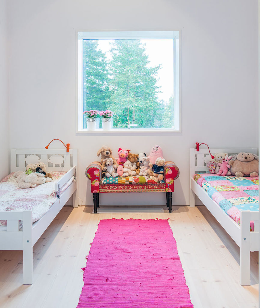 Small girl's bedroom with a small twin bed set on the hardwood flooring topped by a pink rug.