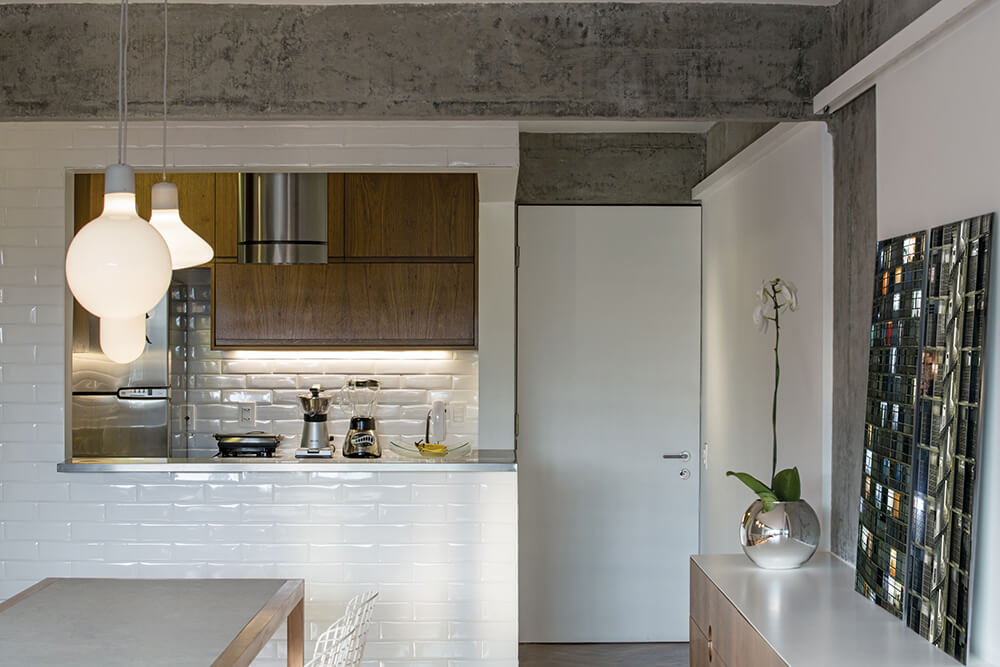 This industrial kitchen features white walls and countertops. The pendant lights are just so attractive.
