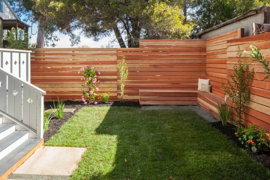 A horizontal slatted privacy fence of wood. A horizontal slatted privacy fence of wood.