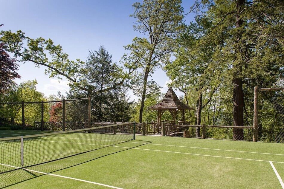 Backyard tennis court surrounded by chain link fence