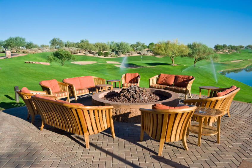 Large round brown brick fire pit on a matching brick patio over looking a golf course. Large round brown brick fire pit on a matching brick patio over looking a golf course.
