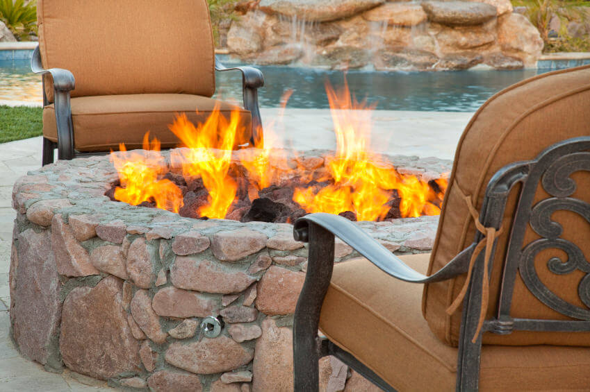 Close-up of a round stone fire pit built onto a brick patio overlooking the pool. Close-up of a round stone fire pit built onto a brick patio overlooking the pool.