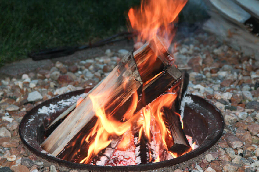 Small pit style fire pit with inverted metal dome inserted into the ground surrounded by gravel. Small pit style fire pit with inverted metal dome inserted into the ground surrounded by gravel.