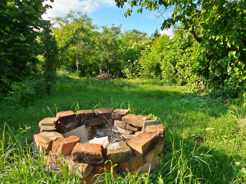 Rustic brick round wood-burning fire pit placed in the middle of the meadow. Rustic brick round wood-burning fire pit placed in the middle of the meadow.