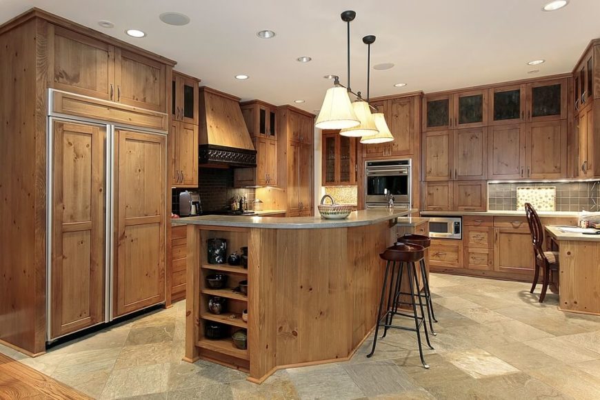 This kitchen has a bit of a vintage feel to it, especially with the faux panels covering the refrigerator. The focus here is on the natural wood of the cabinetry, along with the textured stone flooring. This kitchen has a bit of a vintage feel to it, especially with the faux panels covering the refrigerator. The focus here is on the natural wood of the cabinetry, along with the textured stone flooring.