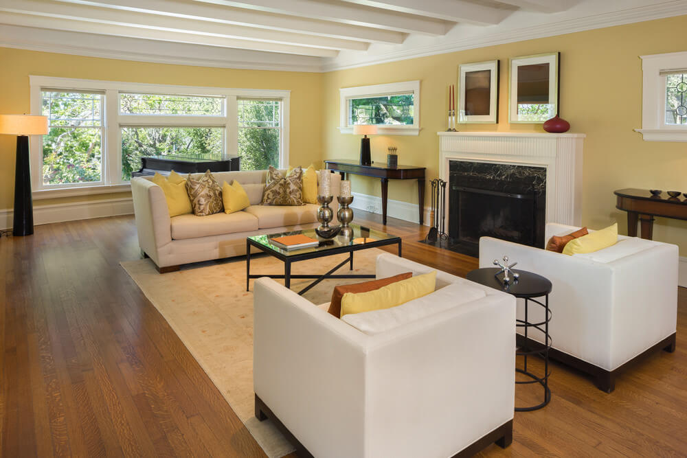 Make your living room calming and inviting by using lighter shades of brown or even yellow for your walls and accentuated with light grey fixtures and furnishings. With this color scheme, it will allow your living room to glow more naturally and accentuate its size. Large living room featuring hardwood flooring and cozy seats. It has a fireplace as well.