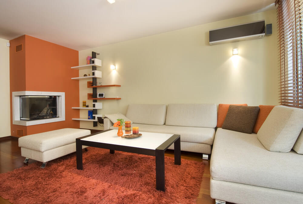 Use a nice shade of muted yellow for your walls to make your living room somehow expand in size as the colors allow more light to dance around. Use orange and brown accents – from the floor to fixtures to add to the inviting aura your living room now has. A closer look at this living room's modern L-shaped sofa set with a fireplace and built-in shelves on the side.