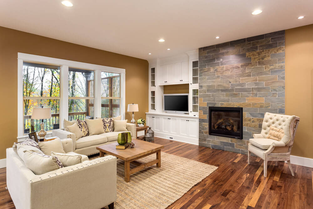Play with different brown blends for your living room – from your walls to your floors – as it can actually calm your mind and give a homey feel. Use a darker shade of brown for your flooring and compliment it with lighter brown blends for the walls. Accentuate it with creams and even white to blend with your living room. Spacious living room featuring hardwood flooring, classy seats and a fireplace, surrounded by brown walls.