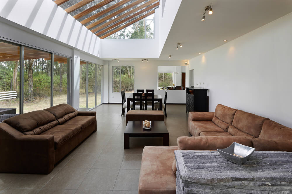Want something modern and yet a classic feel for your living room? Try out this color scheme. Similar to number 21, brown furnishings for your sofa and cushions while your tables and other furniture are in deep black or marble grey. Large great room boasting elegant brown seats and a ceiling with skylight. The room is surrounded by white walls.