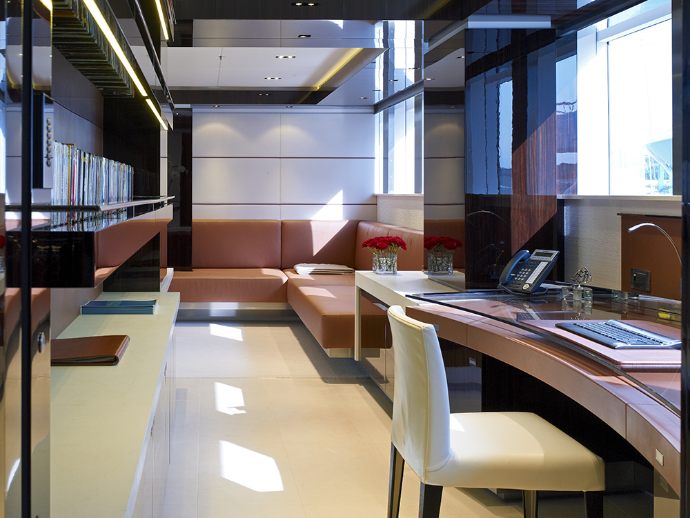 An owner's studio employed with leather covered sofa embracing the corner of the walling and a cream colored chair with a wood and glass top office desk. Macassar ebony touched book shelves are also installed on the wall with additional space provided by white cabinet underneath. An owner's studio employed with leather covered sofa embracing the corner of the walling and a cream colored chair with a wood and glass top office desk. Macassar ebony touched book shelves are also installed on the wall with additional space provided by white cabinet underneath.