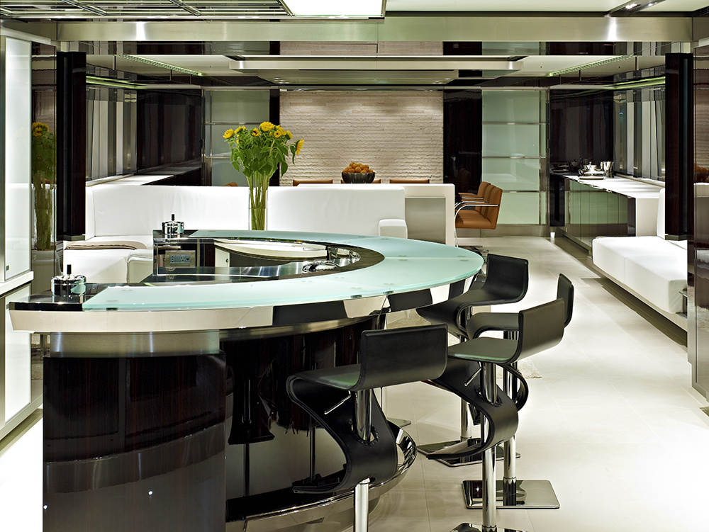 Another star of this yacht's interior is the ergonomic bar area with customized glass table in arched form. While the black leather bar stools are classy and chic, the white leather sofa itself serves as the divider between the living and bar area. The rough and unsmoothen limestone texture provides a rugged look of the dining area. Another star of this yacht's interior is the ergonomic bar area with customized glass table in arched form. While the black leather bar stools are classy and chic, the white leather sofa itself serves as the divider between the living and bar area. The rough and unsmoothen limestone texture provides a rugged look of the dining area.
