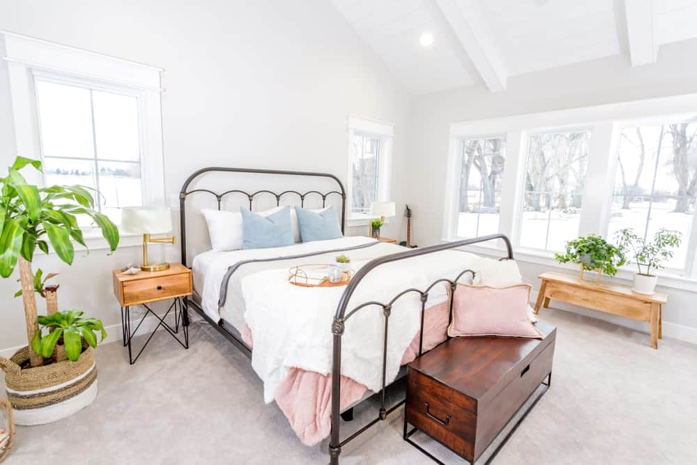 A spacious and bright primary bedroom with green indoor plants adding color to the room.