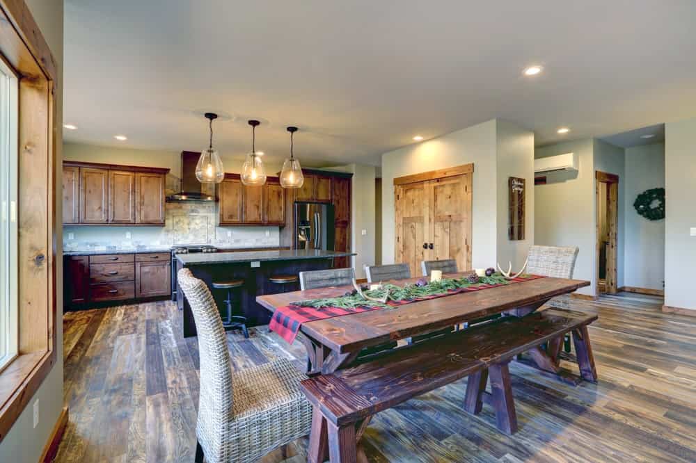 This dining area has a picnic vibe to its wooden dining table and its matching wooden bench with the same wooden finish. This is then augmented by the woven wicker dining chairs that go well with the hardwood flooring.