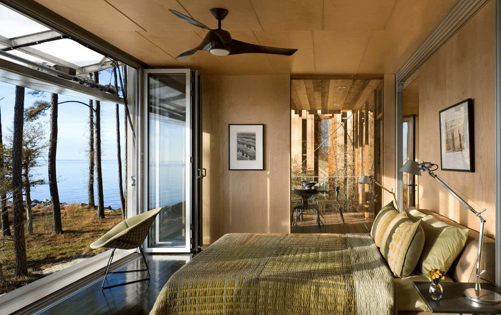 This bright room offers a round chair and upholstered bed dressed in green bedding. It has a folding glass door that opens to the enchanting yard with an oceanfront view.