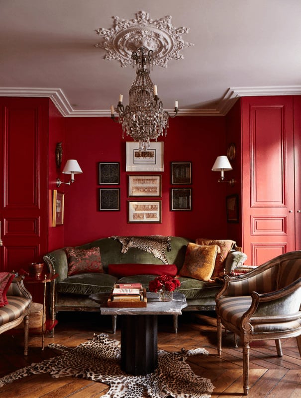 Traditional living room features classy seats and a stylish coffee table lighted by a fabulous chandelier. It has a gallery wall and chevron wood flooring topped by a leopard rug.