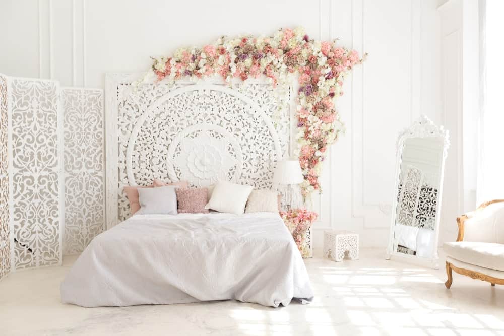 A focused shot at this primary bedroom's lovely bed setup surrounded by white walls and white decors that makes the room so bright.