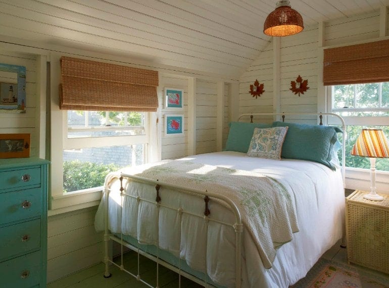 A focused shot at this primary bedroom's comfy bed surrounded by white walls, hardwood floors and a wooden ceiling.