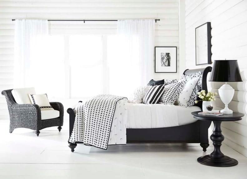 Bright primary bedroom with a black accent. It has white flooring and white walls, along with a black bed frame and other furniture finished in black.