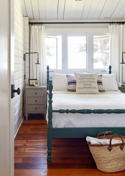 A focused shot at this primary bedroom's bed set near the windows. The room features hardwood flooring and a wooden ceiling.