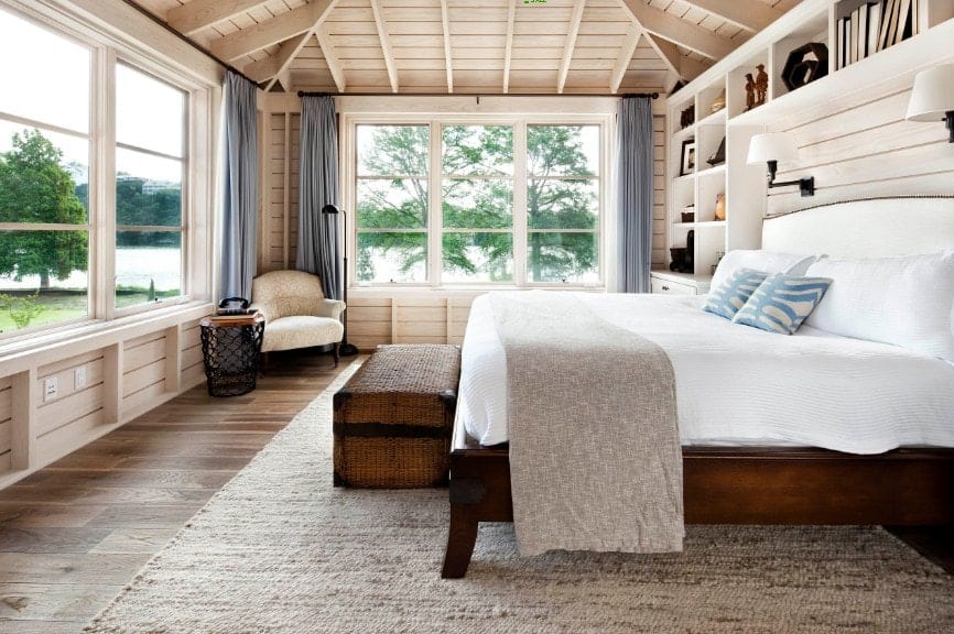 Spacious primary bedroom featuring wooden walls and hardwood flooring, along with a wooden ceiling. The room has a large bed and has multiple built-in shelves.