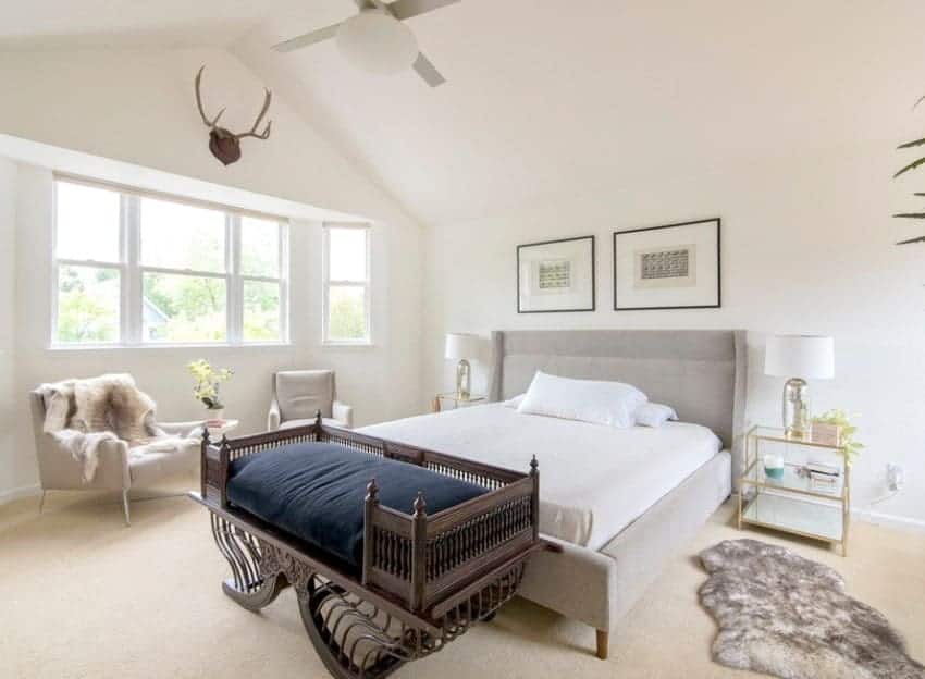 This Scandinavian-Style primary bedroom boasts classy carpet flooring and a luxurious bed under the white vaulted ceiling.