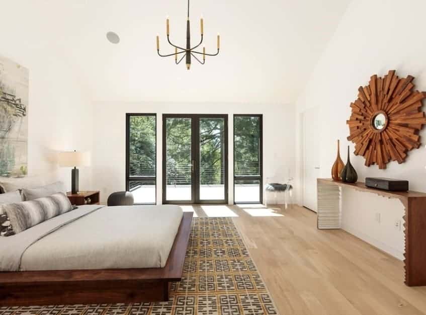 Large Scandinavian-Style primary bedroom with a gorgeous chandelier lighting up space. The bed looks classy together with the wall decors.