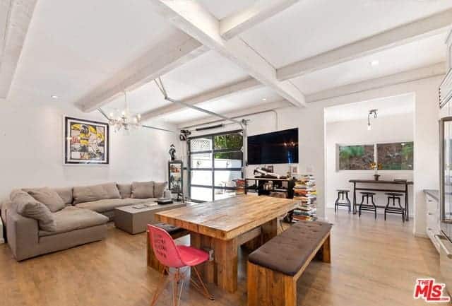 This informal dining area is in between the living room area and the kitchen that has the same white coffered ceiling and hardwood flooring that complements the wooden table and its wooden benches that has a dark brown cushion on top.
