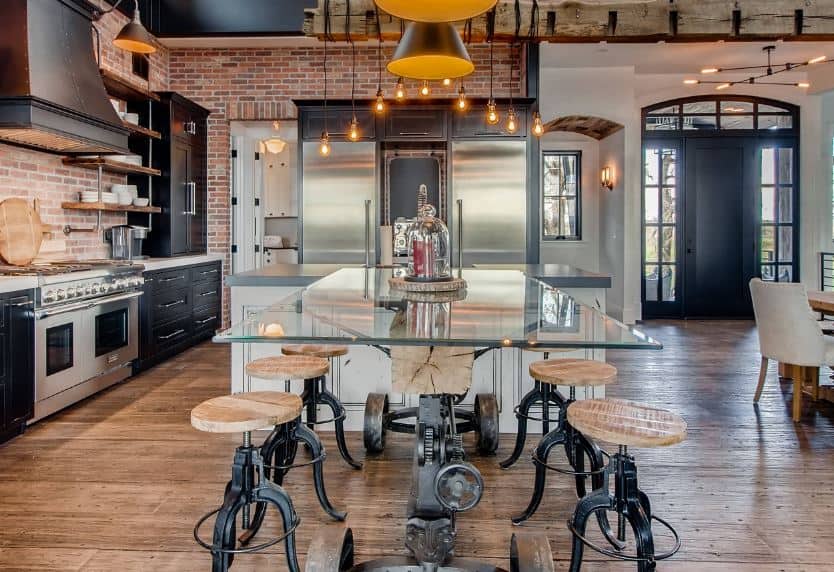 The red brick walls makes the black cabinets of the peninsula stand out along with the stainless steel appliances that it houses. This is complemented by a hardwood flooring and a gray concrete ceiling with exposed vents and wirings.