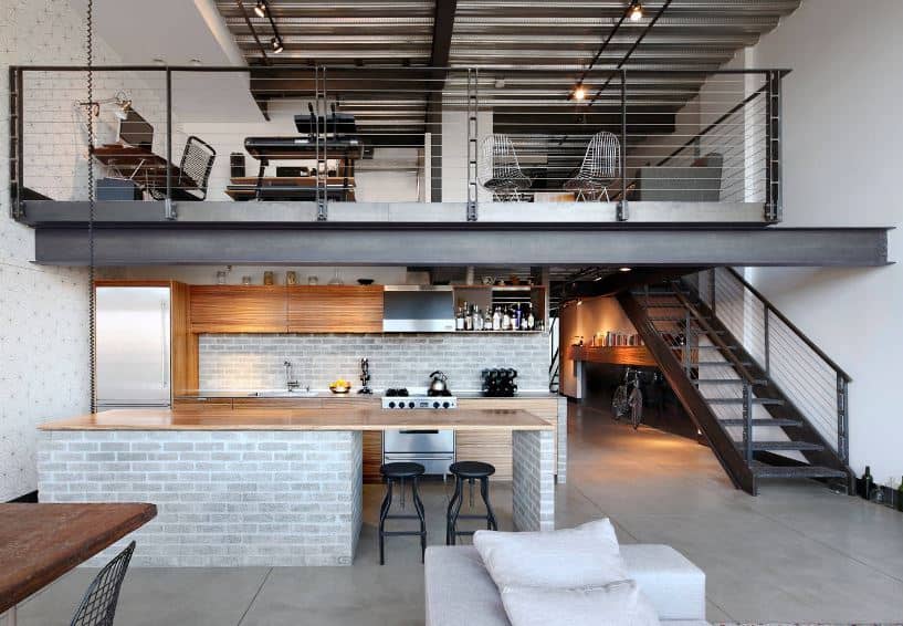 This charming kitchen is framed on two sides by the black metal beam above that supports the loft and the black metal beam of the stairs on the right. This gives a nice contrast to the light hue of the brick walls that match the kitchen island.