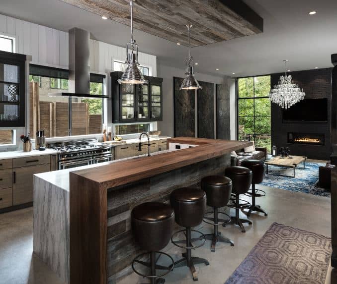 Those beautiful stainless steel pendant light hanging over the kitchen island matches with the stainless steel appliances of the cooking area embedded in the kitchen peninsula that has wooden drawers and cabinets.