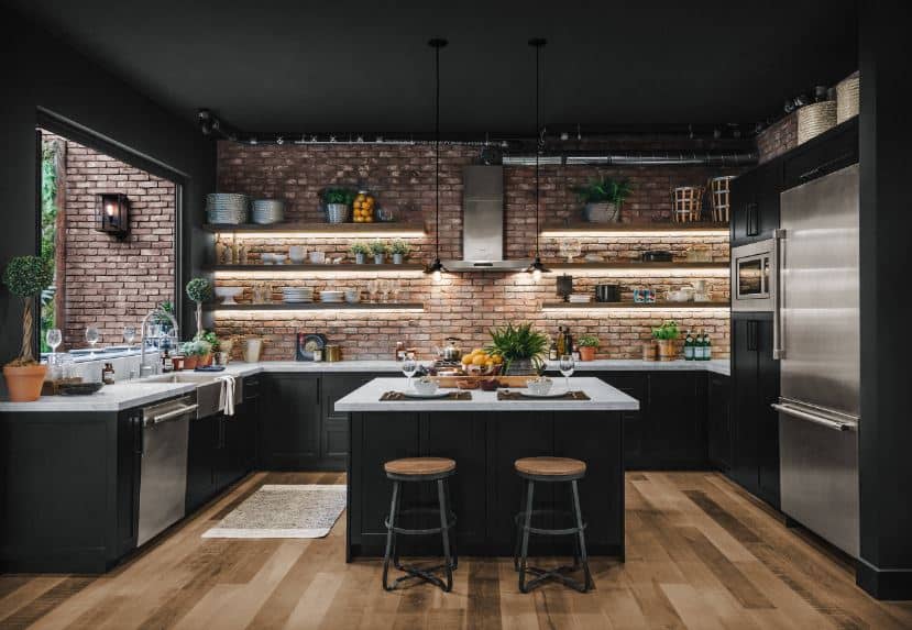 This kitchen is dominated by the black hues of the shaker cabinets and drawers of the kitchen island and U-shaped peninsula as well as the black ceiling. This is complemented by the red brick walls and the hardwood flooring.