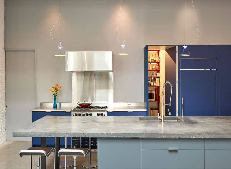 This kitchen is a combination of modern elements with the industrial-style kitchen. It has a kitchen island with modern light blue cabinets with a gray concrete countertop. This pairing is mirrored by the light gray walls and the blue peninsula cabinets.