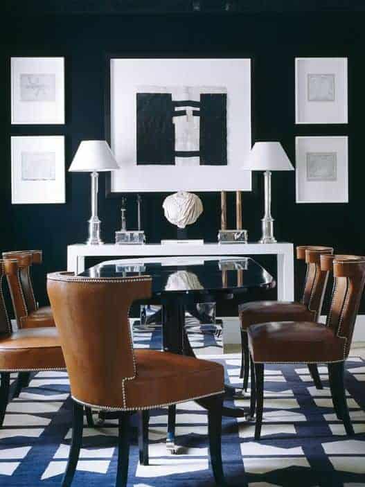 The brown leather cushioned wing back chairs serve as a medial element to the contrasting black and white elements like the black dining table and black walls contrasted by the white console table and wall-mounted framed artworks.