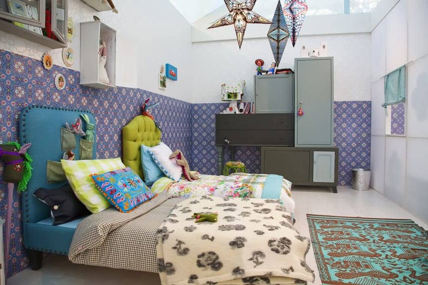 Shared kids bedroom boasts gorgeous blue and green beds along with modular cabinets that are placed against the white walls dominated by lovely floral wallpaper.